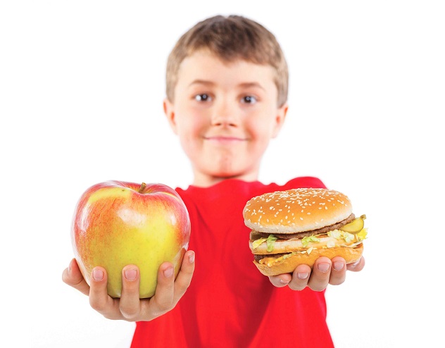 Мальчик держит в руках яблоко и гамбургер