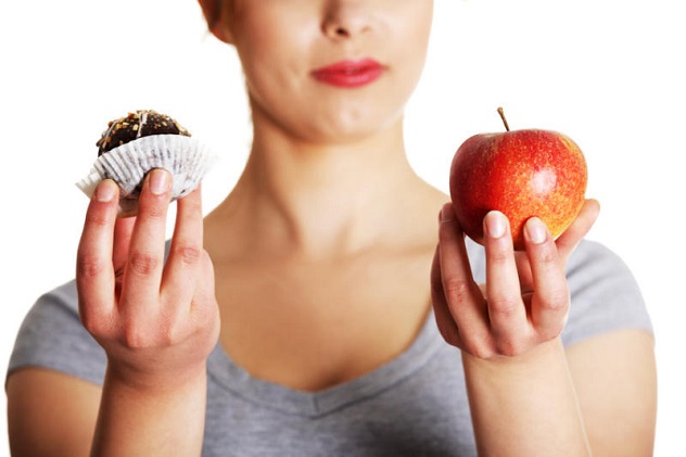 Женщина выбирает скушать яблоко или пирожное
