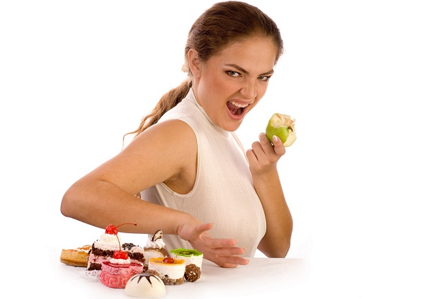 Девушка ест яблоко и отказывается от сладостей