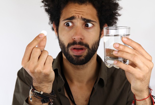 Мужчина держит таблетку и стакан с водой