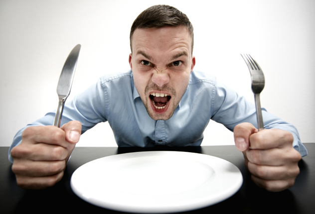 Голодный мужчина кричит возле пустой тарелки