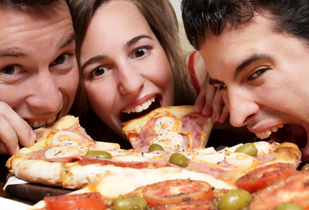 Женщина и мужчины едят пиццу