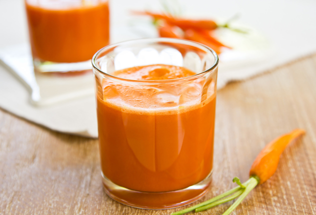 Морковный сок в стакане и маленькая морковь