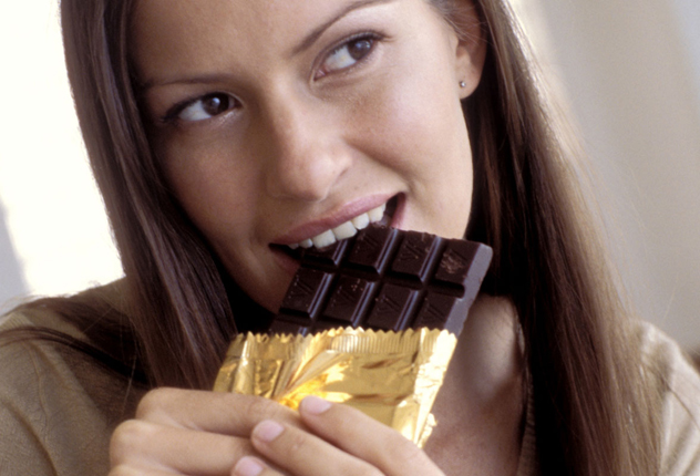 Девушка кушает шоколад с золотой оберткой