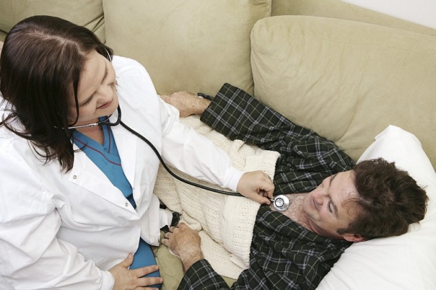 Мужчина лежит на диване и врач его обследует