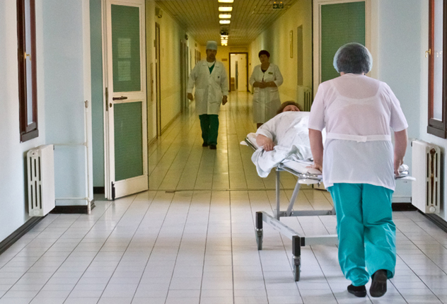 Медсестра везет кушетку с больным по коридору больницы