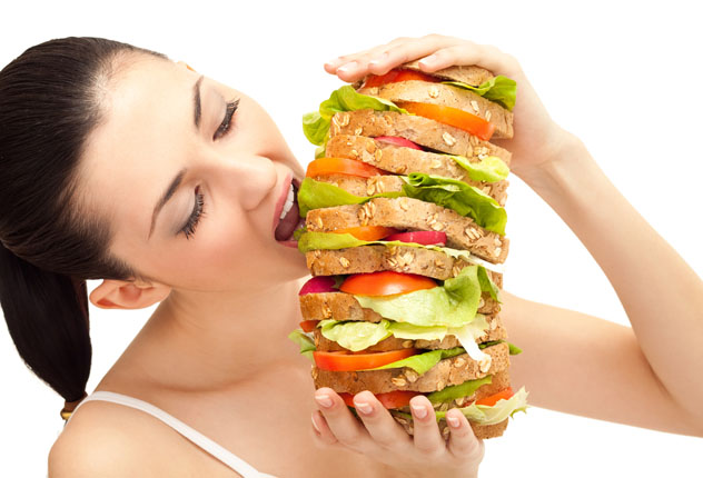 Женщина кушает огромный бутерброд
