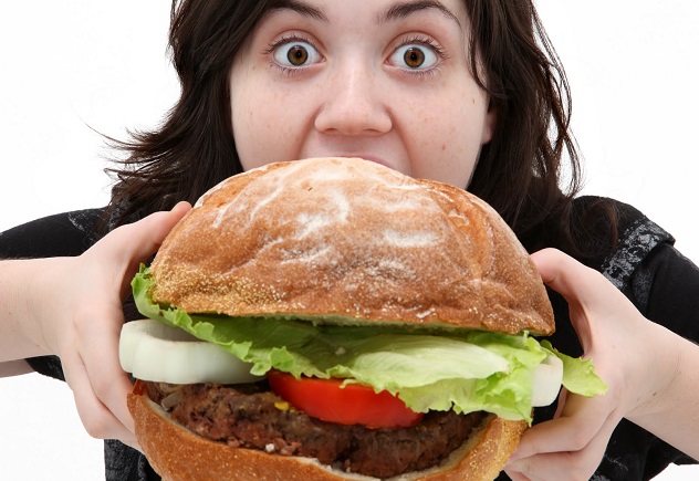 Женщина кушает огромный гамбургер