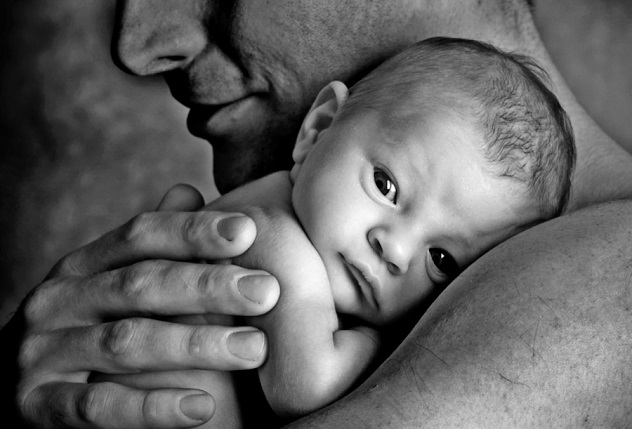 Папа держит на руках новорожденного ребенка