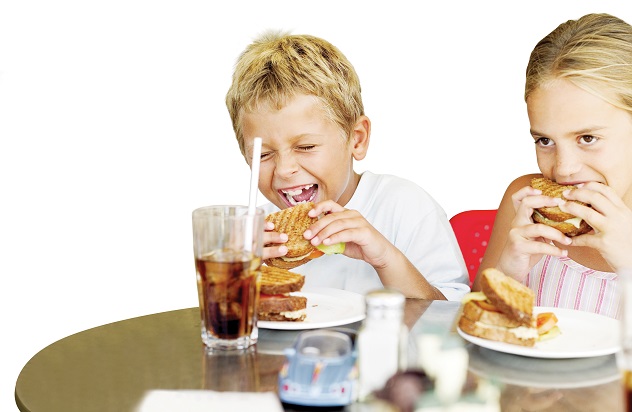 Мальчик и девочка смеются и едят бутерброды