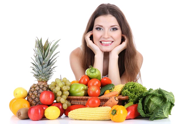 Девушка сидит за столом с овощами и фруктами