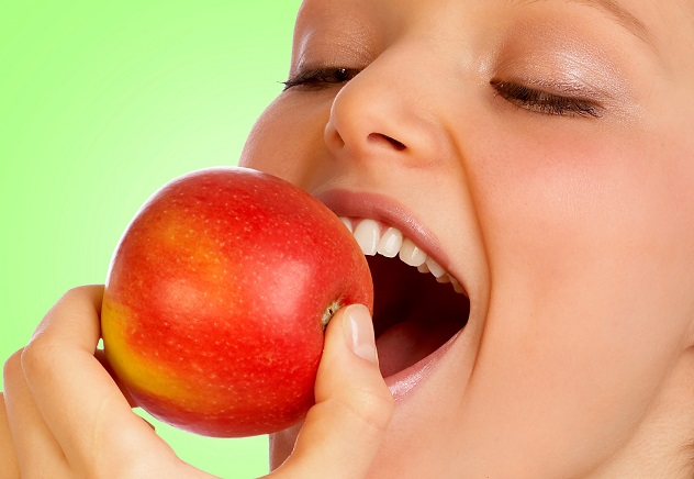 Девушка грызет красное яблоко