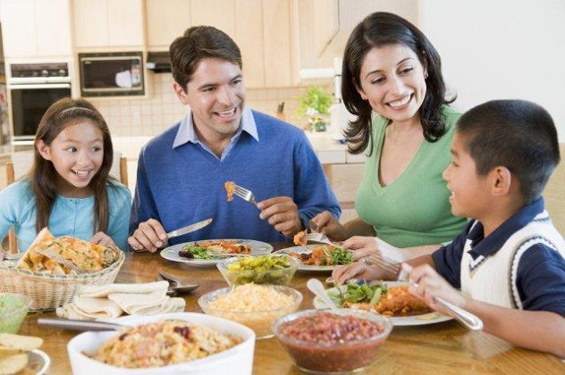 Счастливая семья кушает за столом здоровую пищу