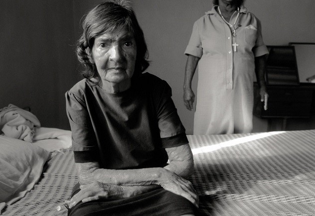 Пожилая пациентка сидит на кровати в больнице