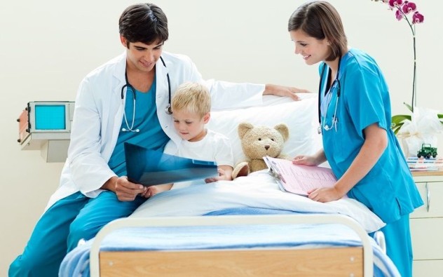 Ребенок сидит на кровати с врачом и смотрит на снимок