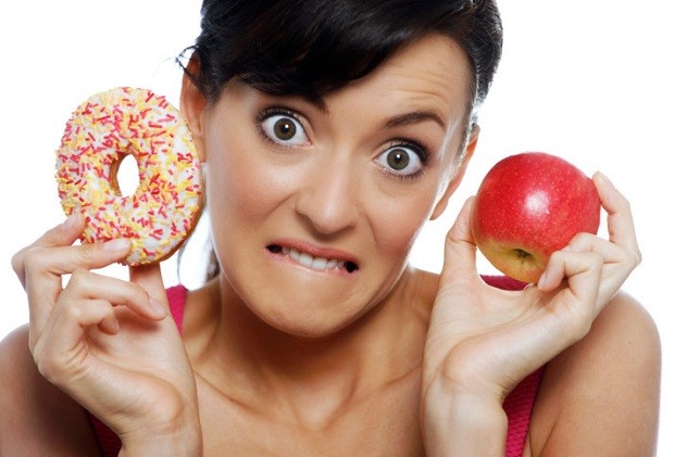 Женщина выбирает между пончиком и яблоком