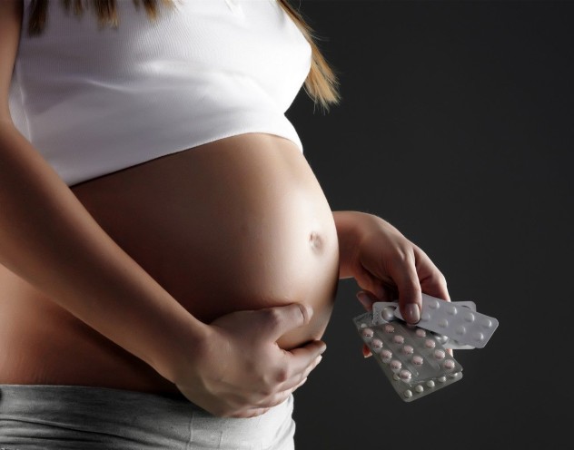 Таблетки в руках у беременной женщины