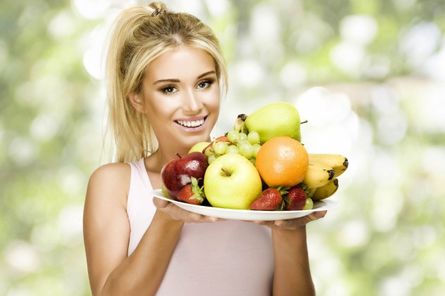 Девушка держит свежие фрукты на блюде
